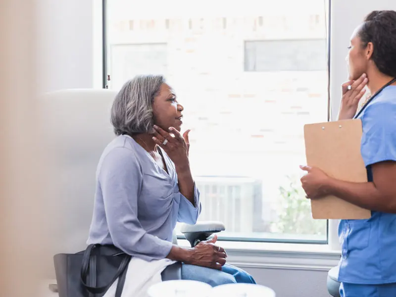 A woman in conversation with a care professional by a window