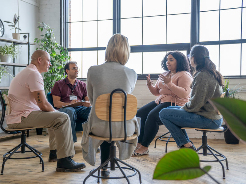 A small group seated in a circle in a bright room