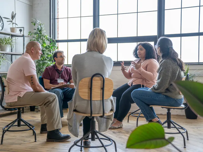 A small group seated in a circle in a bright room