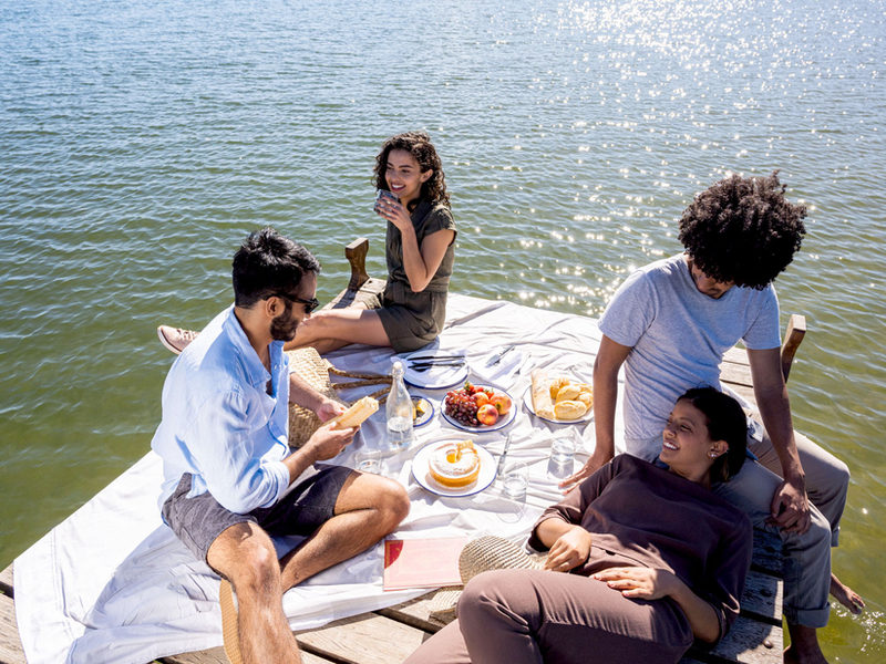 Friends sharing a picnic on a sunlit dock by the water