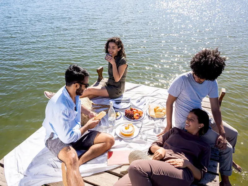 Friends sharing a picnic on a sunlit dock by the water